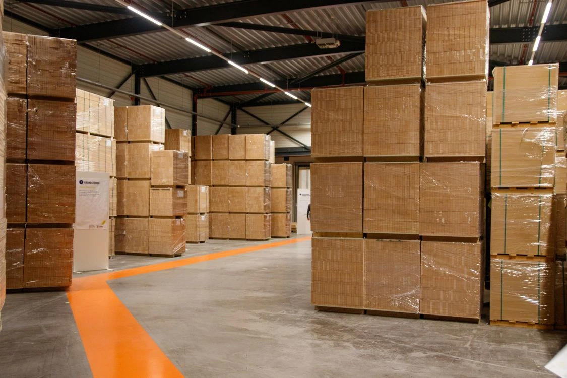Kartonversand24 – Lager & Versand – Verpacken und Versand Versandkartons gestapelt im industriellen Lager